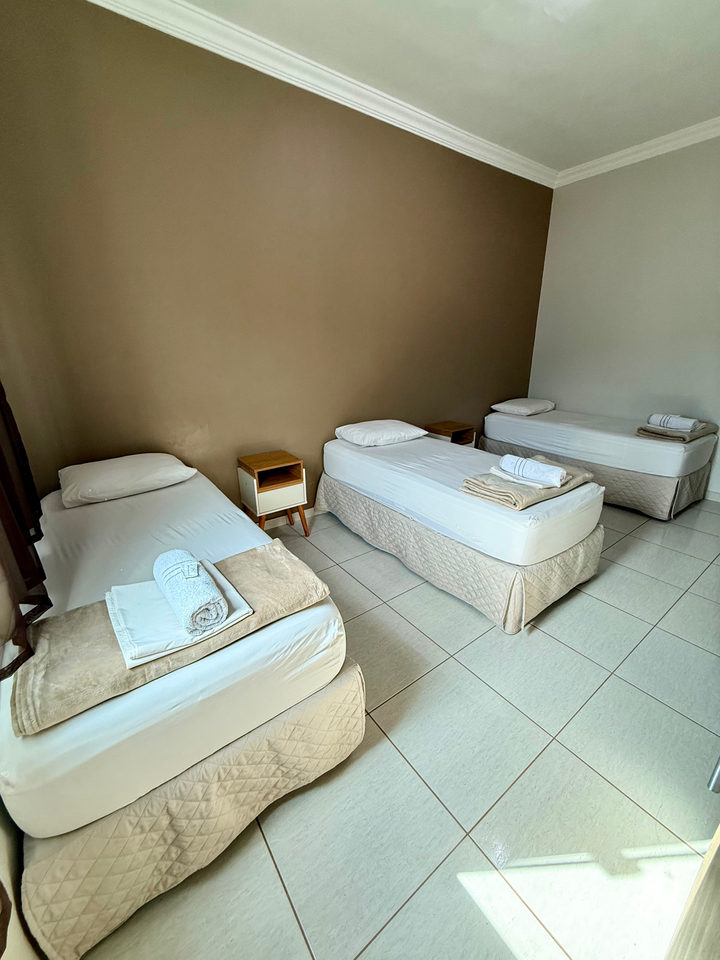 Três camas de solteiro no apartamento de parede marrom