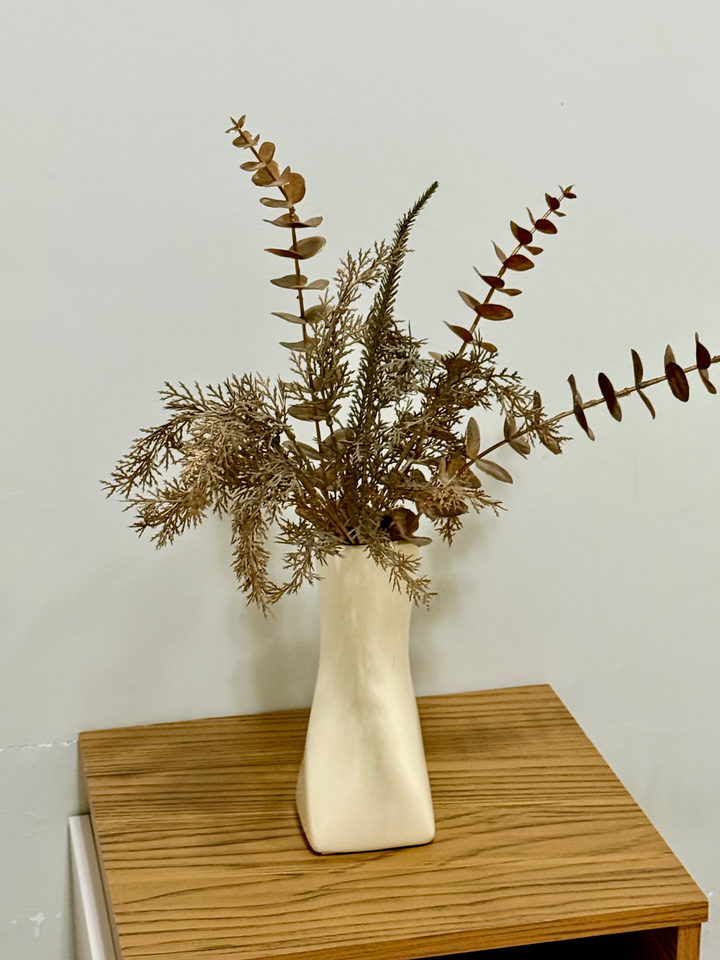 Arranjo de flores secas em vaso sobre o criado-mudo